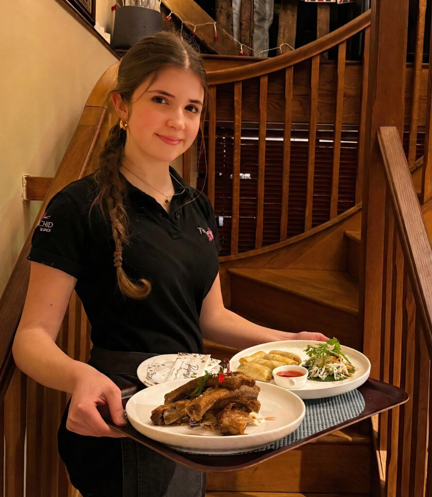 Waitress serving Thai dishes at Thai Orchid Battle